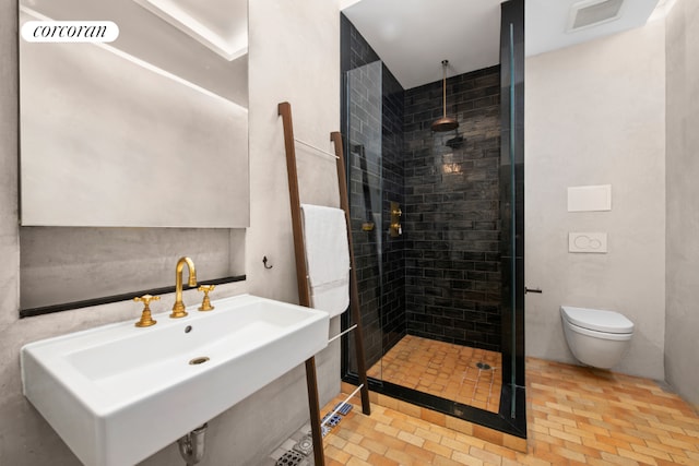 bathroom with sink, toilet, and tiled shower