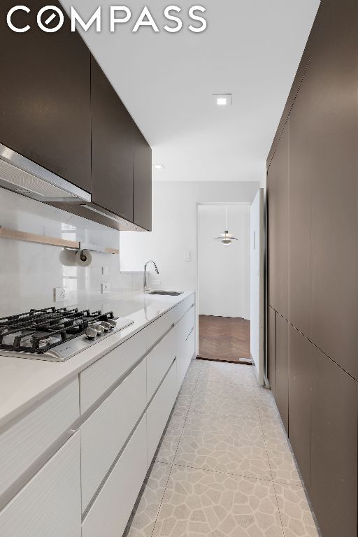 kitchen with white cabinetry, stainless steel gas cooktop, and sink