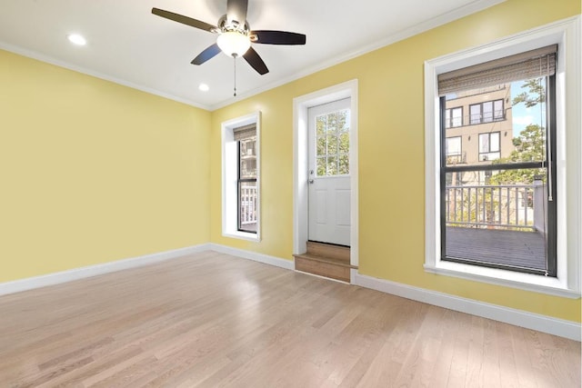 empty room featuring ceiling fan, ornamental molding, plenty of natural light, and light wood-type flooring