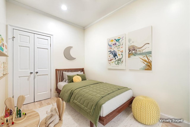 bedroom featuring light hardwood / wood-style flooring, ornamental molding, and a closet