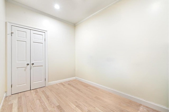 empty room with crown molding and light hardwood / wood-style flooring