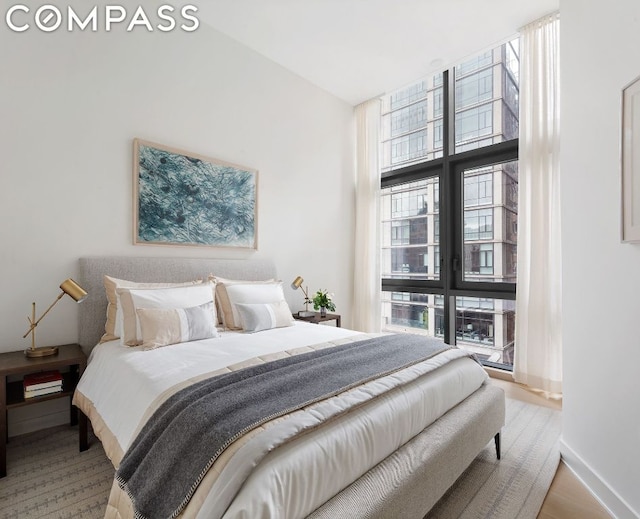 bedroom with floor to ceiling windows, light hardwood / wood-style floors, and multiple windows