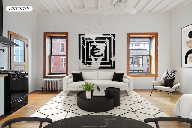 living room with radiator, baseboards, beam ceiling, and wood finished floors