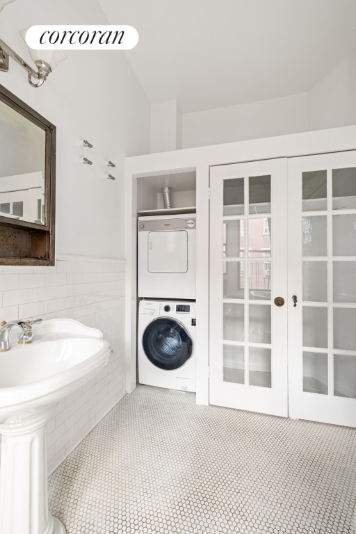 interior space with stacked washer / dryer, sink, and tile patterned flooring