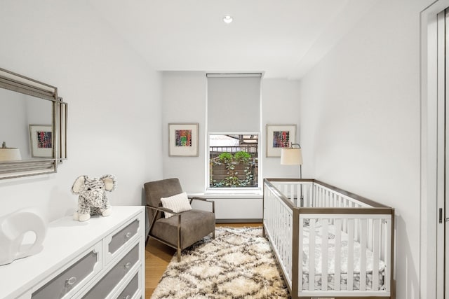 bedroom featuring a crib and light wood-style flooring