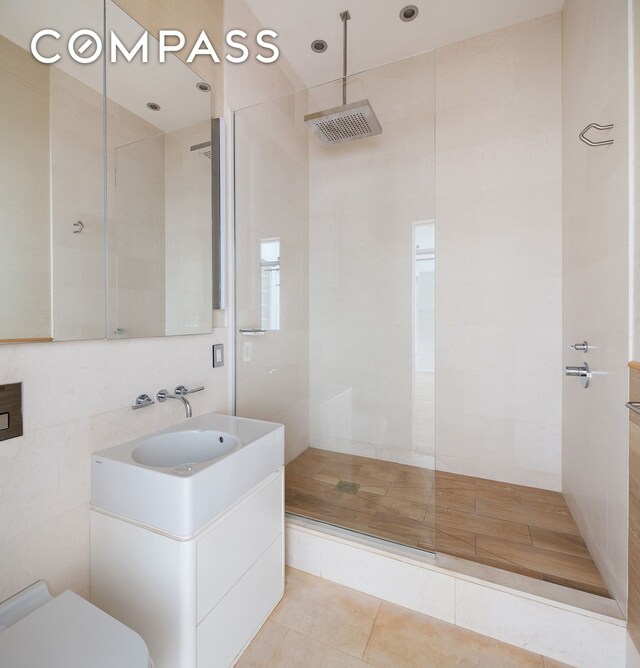 22 E 18th St Unit 4E, New York City, NY 10003 - bathroom featuring toilet, a walk in shower, vanity, tile patterned floors, and tile walls