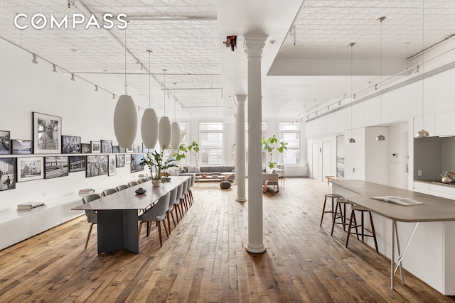 dining space featuring an ornate ceiling, wood-type flooring, a towering ceiling, and ornate columns