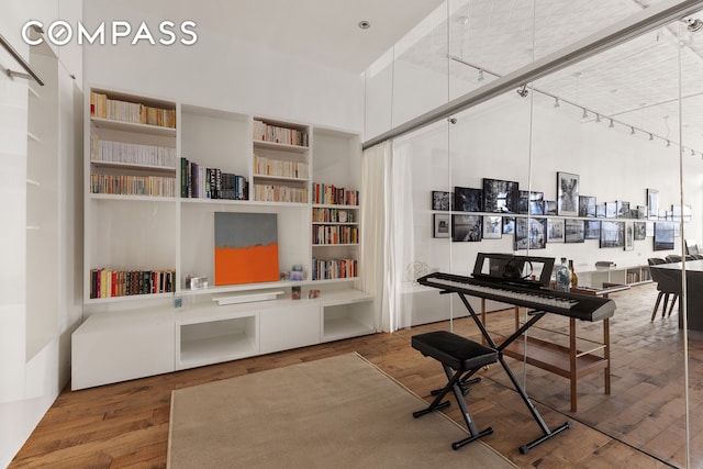 office area featuring track lighting, a towering ceiling, and wood-type flooring