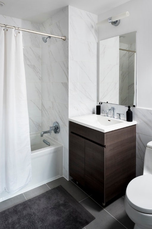 full bath featuring toilet, vanity, tile walls, tile patterned floors, and shower / bath combo with shower curtain