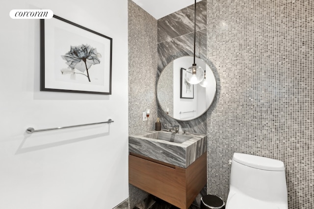 bathroom featuring toilet, tile walls, backsplash, and vanity