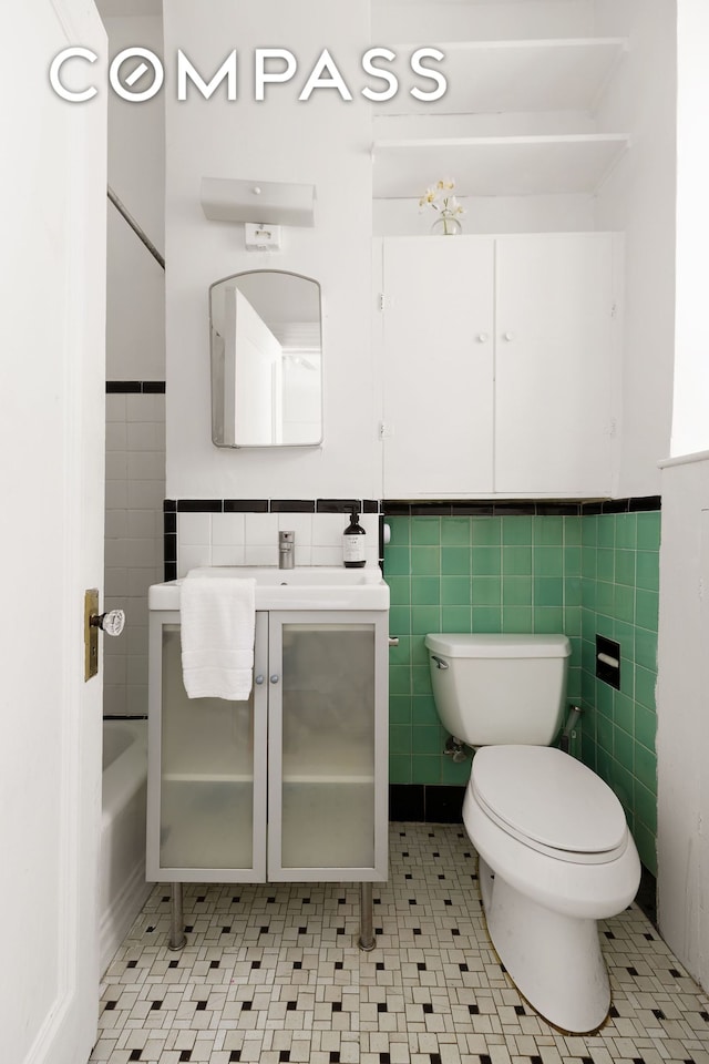 full bathroom featuring wainscoting, vanity, toilet, and tile walls