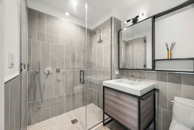 full bath with vanity, a shower stall, toilet, and tile walls