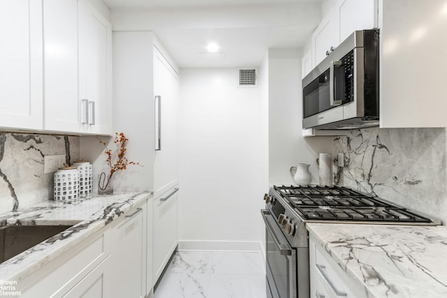 kitchen with stainless steel appliances, white cabinetry, visible vents, marble finish floor, and light stone countertops