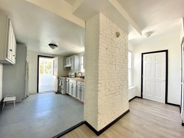 kitchen with white cabinetry, sink, gas range gas stove, and light wood-type flooring