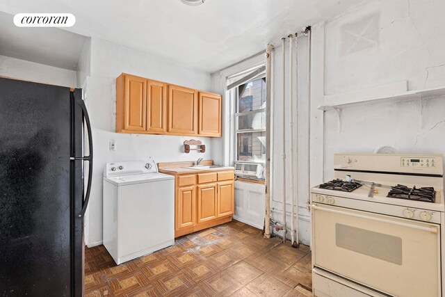 kitchen featuring white gas range, washer / clothes dryer, visible vents, freestanding refrigerator, and a sink