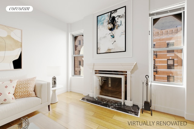 living room featuring a glass covered fireplace, wood finished floors, visible vents, and baseboards