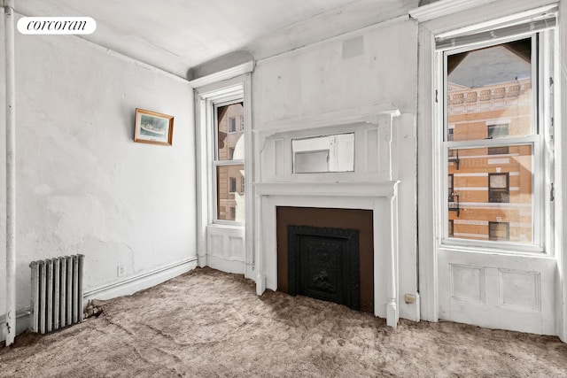 unfurnished living room featuring radiator, carpet floors, a fireplace, and visible vents