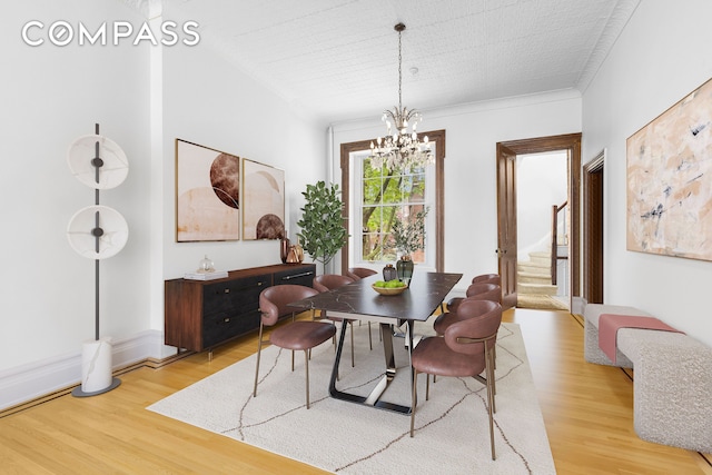 dining area with a chandelier, stairway, light wood-type flooring, and crown molding