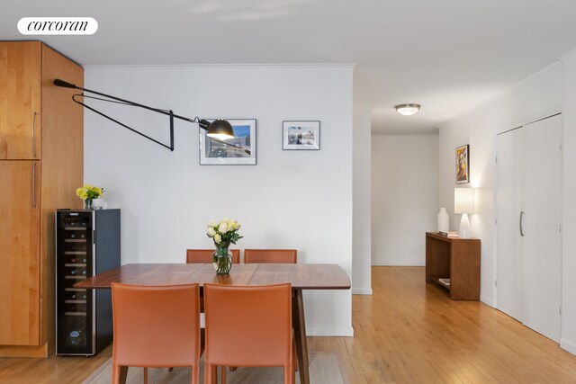 dining room with light wood-style floors, wine cooler, visible vents, and crown molding