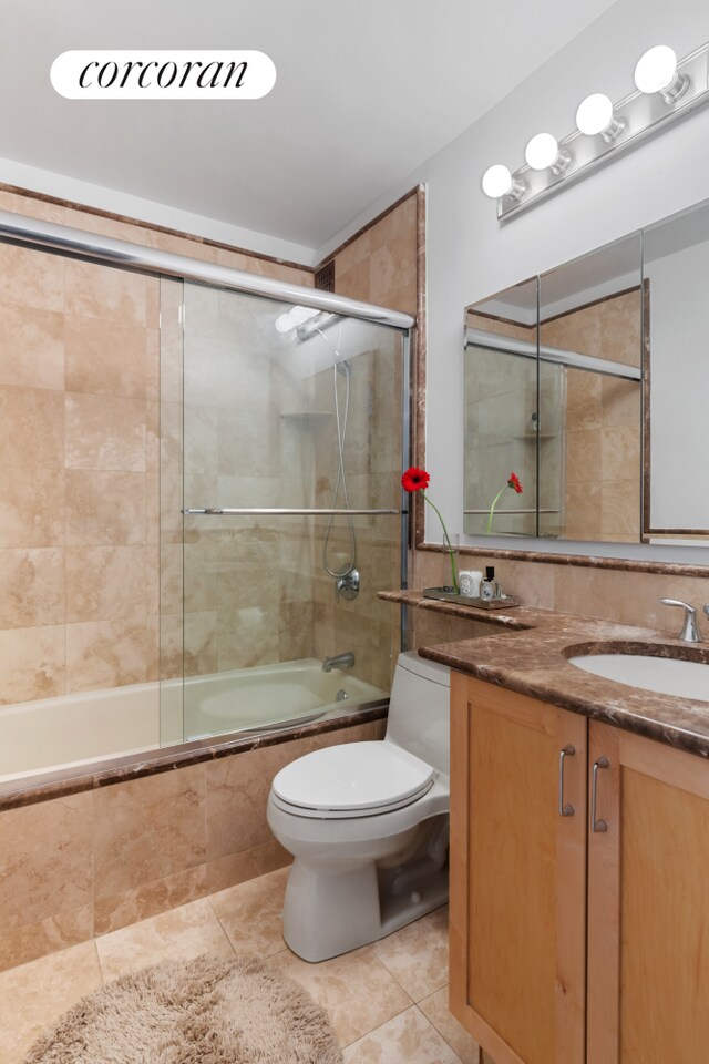 bathroom with tasteful backsplash, toilet, tile patterned floors, tiled shower / bath combo, and vanity