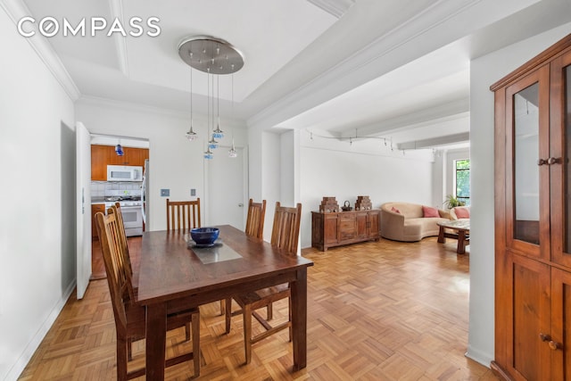 dining room featuring a tray ceiling, baseboards, and ornamental molding