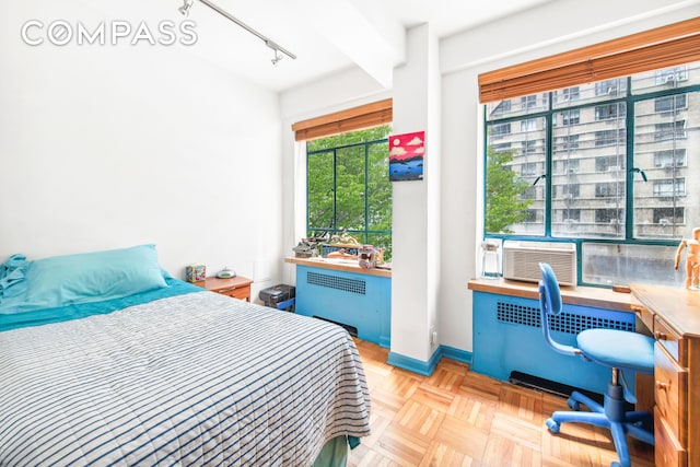 bedroom featuring radiator heating unit, track lighting, cooling unit, and baseboards
