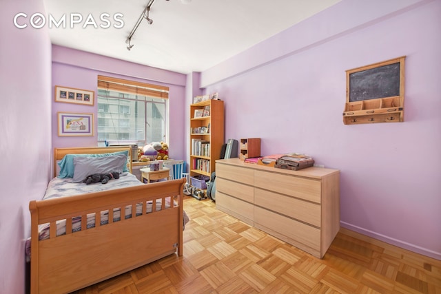 bedroom featuring track lighting and baseboards