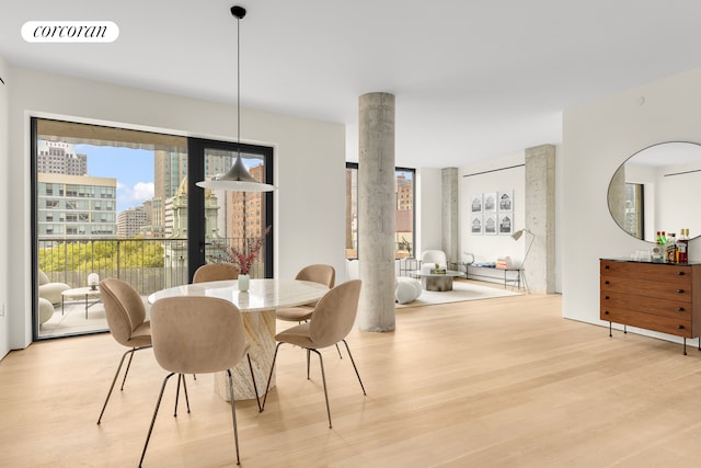 dining space with light wood-type flooring, visible vents, and a city view