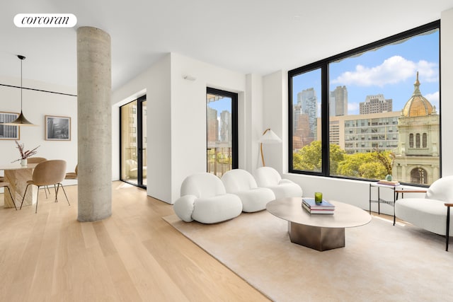 living area with wood-type flooring and decorative columns