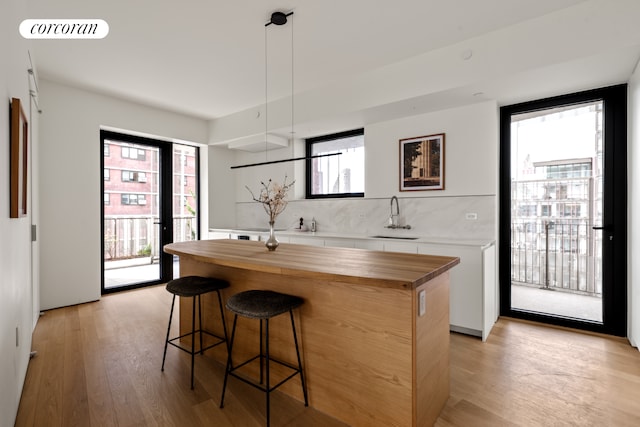 9 Chapel St Unit 8A, New York City, NY 11201 - kitchen featuring light wood-style flooring, a breakfast bar area, a sink, wood counters, and white cabinets