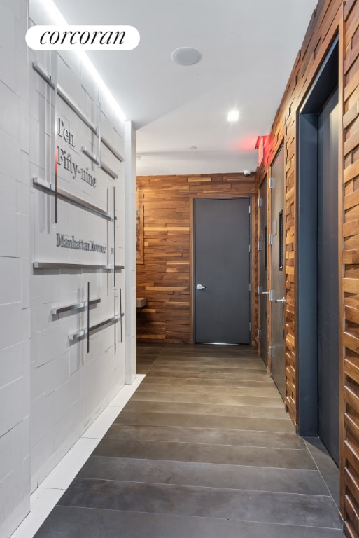 corridor featuring dark wood-type flooring and wooden walls