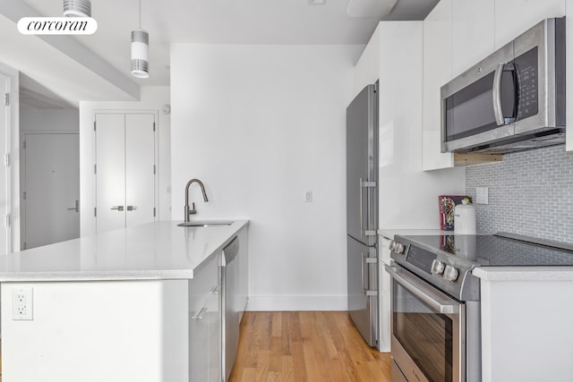 kitchen featuring white cabinetry, stainless steel appliances, backsplash, pendant lighting, and sink