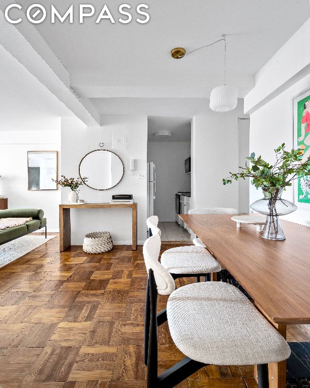 dining room featuring beamed ceiling and dark parquet flooring