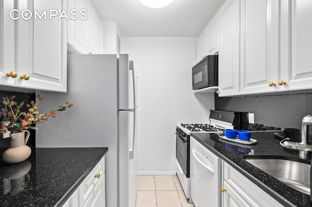 kitchen featuring dark stone countertops, dishwasher, sink, and white cabinets