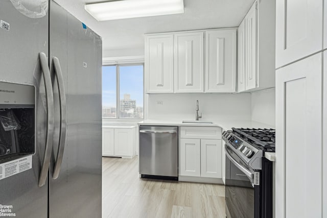 kitchen with white cabinetry, stainless steel appliances, and a sink