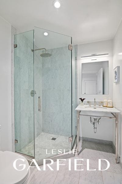 bathroom featuring a stall shower, a sink, and toilet