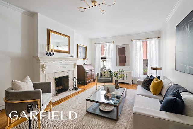 living room with radiator heating unit, a tiled fireplace, wood finished floors, and crown molding