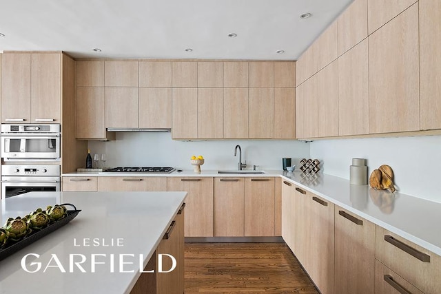 kitchen with a sink, stainless steel double oven, modern cabinets, and light brown cabinets