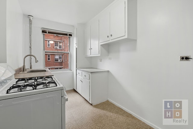 570 Grand St Unit H1504, New York City, NY 10002 - kitchen featuring white range with gas stovetop, light flooring, white cabinetry, and light countertops