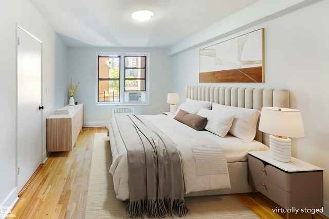 bedroom with radiator heating unit, light wood-type flooring, cooling unit, and visible vents