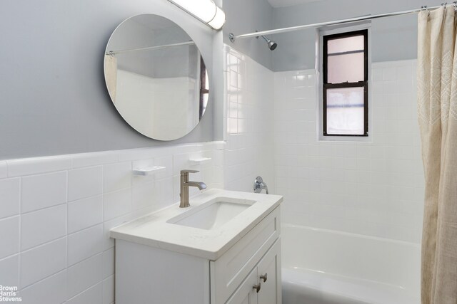 bathroom featuring wainscoting, tile walls, shower / tub combo with curtain, and vanity