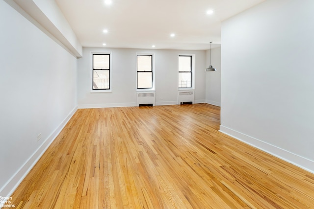 unfurnished room with radiator, light wood-style flooring, baseboards, and recessed lighting