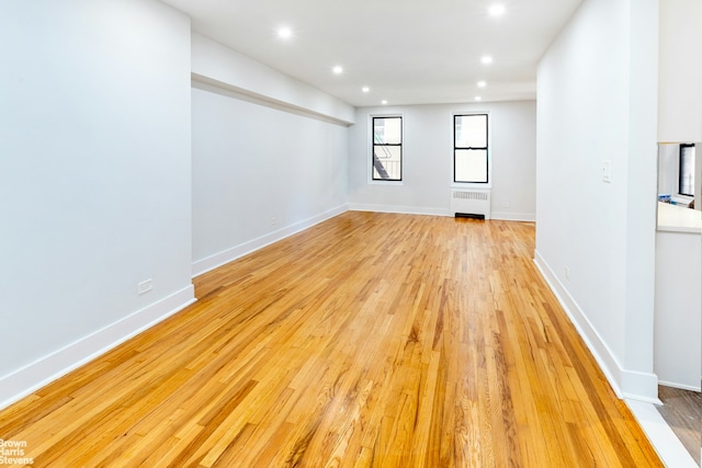 empty room with recessed lighting, radiator, baseboards, and light wood finished floors