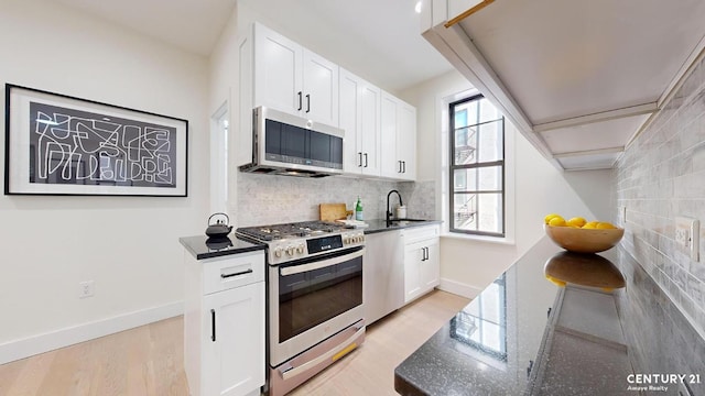 kitchen featuring sink, white cabinetry, appliances with stainless steel finishes, and dark stone countertops