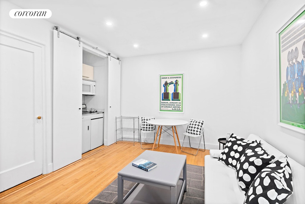 living area with a barn door, recessed lighting, visible vents, and light wood-style floors