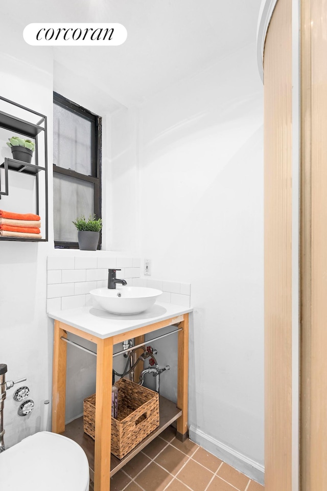 bathroom with baseboards, decorative backsplash, toilet, tile patterned floors, and vanity