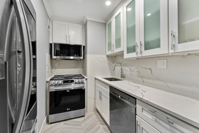 kitchen featuring appliances with stainless steel finishes, white cabinets, glass insert cabinets, and a sink