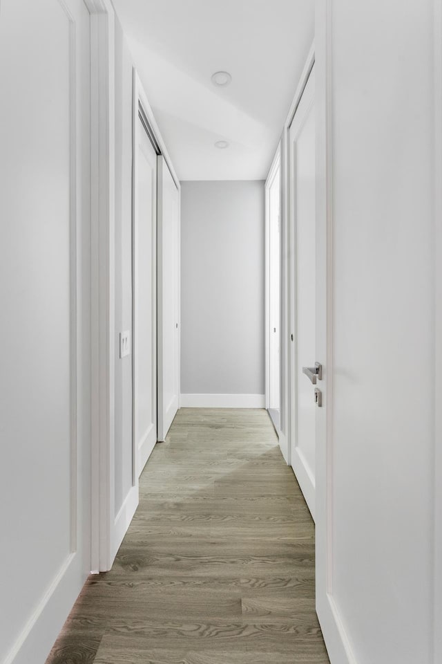 hall with light wood-type flooring and baseboards