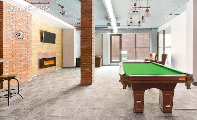 rec room with carpet floors, a fireplace, and brick wall