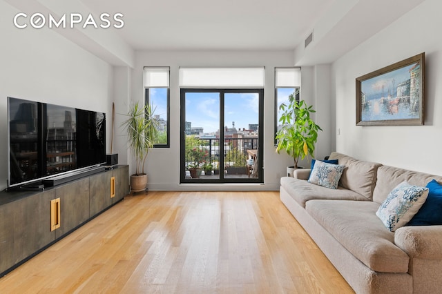 living room featuring visible vents, a city view, and wood finished floors